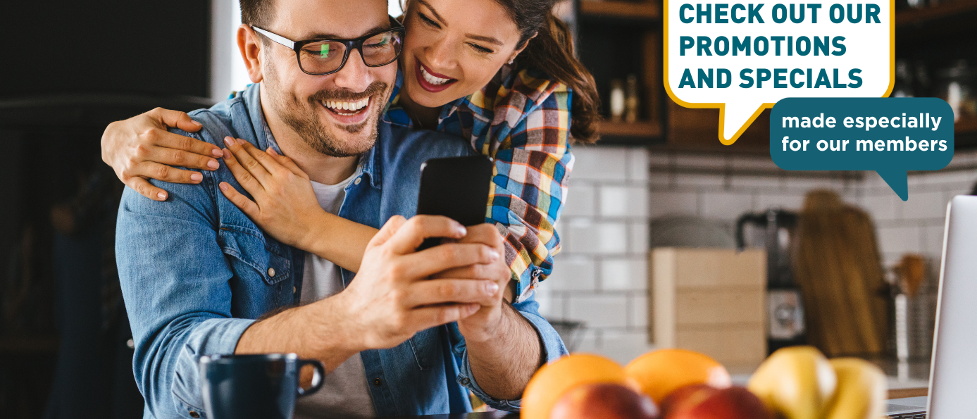 couple smilng and embracing while looking at a smart phone 